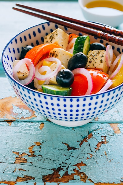 野菜のサラダとオリーブの木製の青い背景上の箸