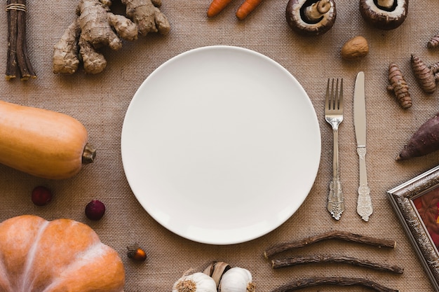 Photo vegetables and sticks around plate and cutlery