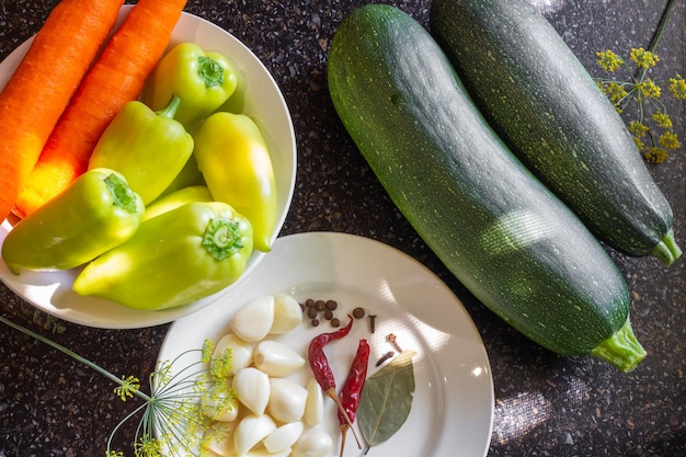 テーブルの上の野菜は、冬のズッキーニにんじん、唐辛子、にんにくの野菜ズッキーニサラダを皿に盛り付けて調理するために用意されています