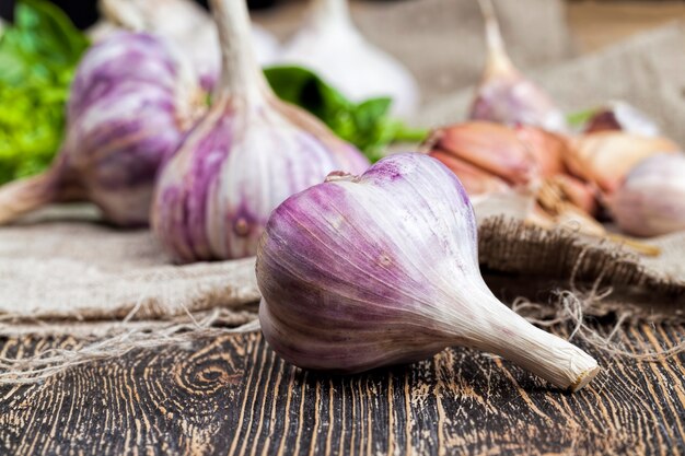 熟した赤にんにくと緑のバジル野菜を調理している間のテーブルの上の野菜とリネンのテーブルクロスボード上のスパイスがクローズアップ