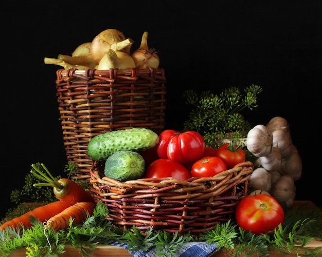 Foto verdure (pomodoro e cetriolo, aglio e aneto, cipolla e carote) in un cestino sul tavolo. raccolta fresca dal giardino.