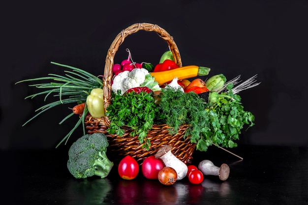 黒の背景に様々 な料理を調理するための枝編み細工品バスケットの食材に野菜