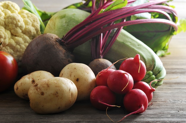 Vegetables on a wooden surface in backlit conditions with radishes, beets, potatoes closeup