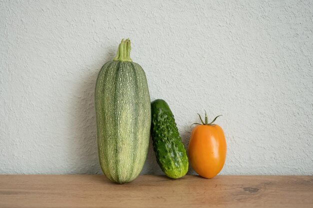 Vegetables on wooden table against white wall