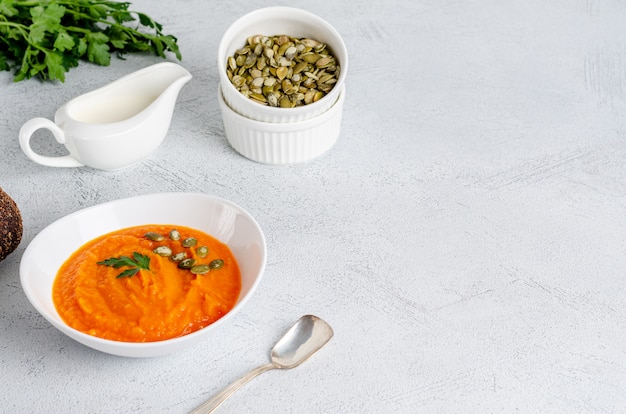 Vegetarian autumn cream soup of pumpkins and carrots with seeds and parsley, flat lay