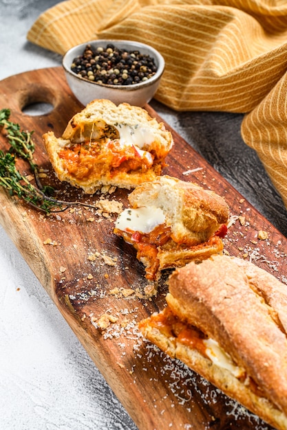 Panino sottomarino vegetariano delle baguette con melanzana arrostita, pepe e feta sulla tavola grigia.