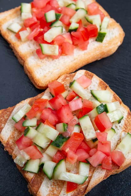 Vegetarian bread toast bruschettas with fresh cucumber and tomato.