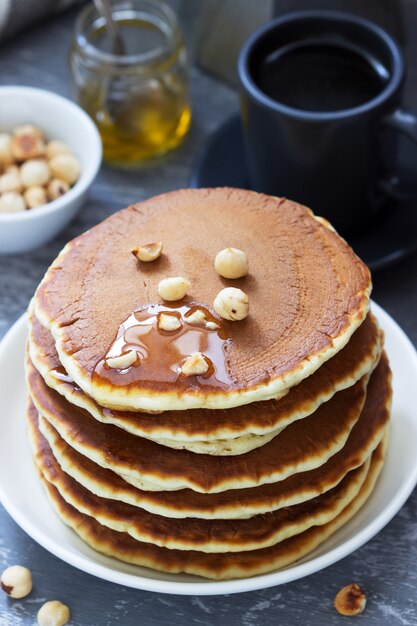 Colazione vegetariana a base di pancake, caffè, miele, noci e frutta.