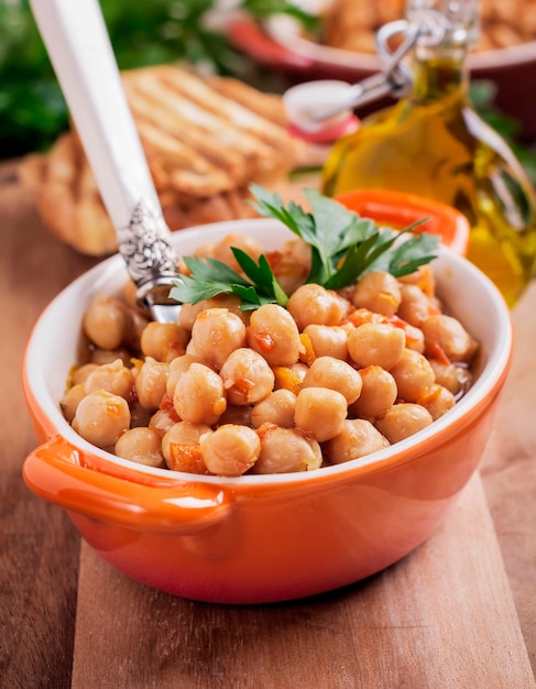 Vegetarian cooked chickpea with tomato and parsley on old wooden background. Selective focus.