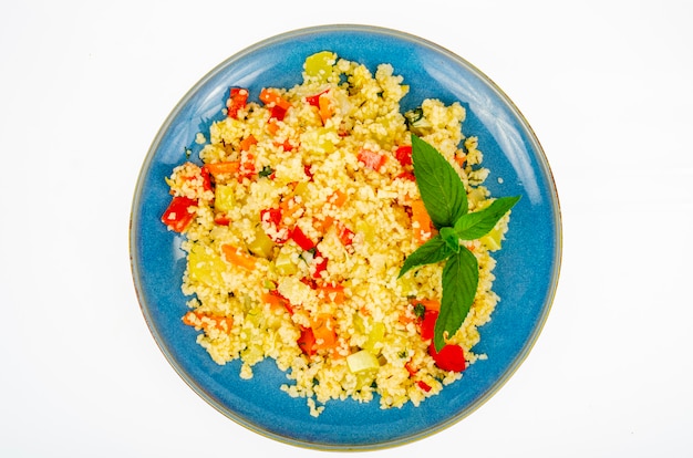 Vegetarian couscous pilaf with vegetables on blue plate. 