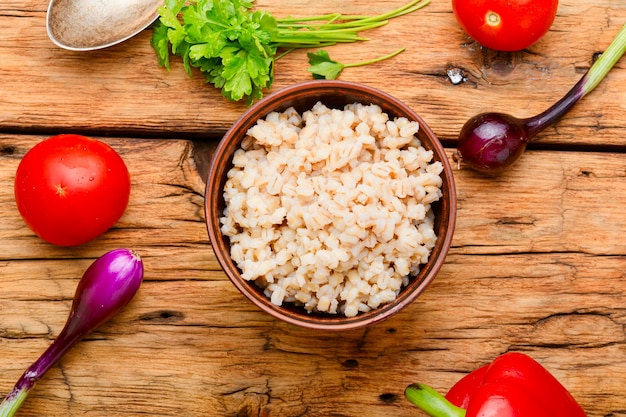 Vegetarian crumbly pearl barley porridge.Pearl barley porridge on wooden background