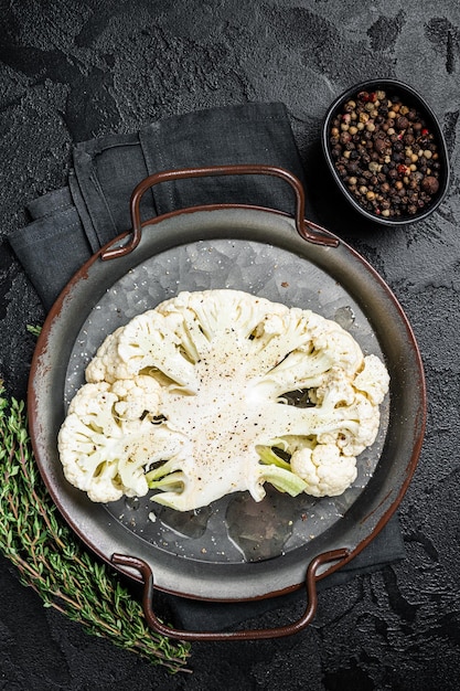 Vegetarian cuisine cooking of cauliflower steak Black background Top view