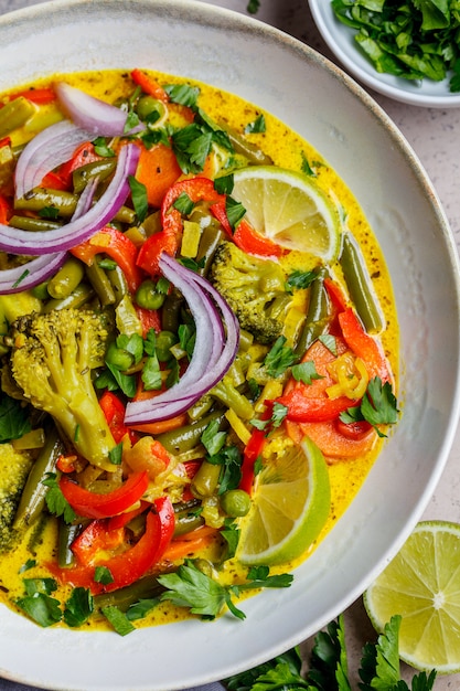 Vegetarian curry with broccoli, pepper, green beans and coconut milk in a bowl, top view.