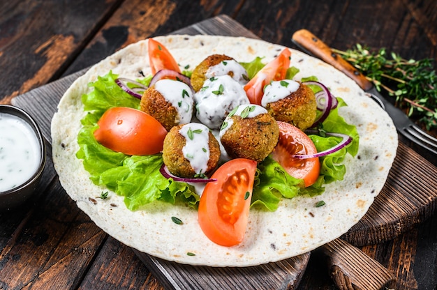 Vegetarian falafel with vegetables and tzatziki sauce on a tortilla bread