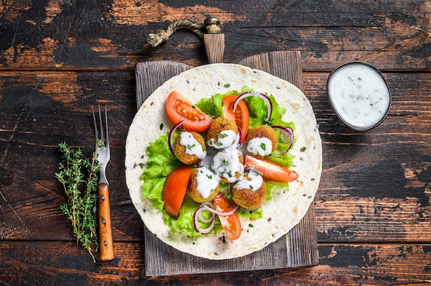 Vegetarian falafel with vegetables and tzatziki sauce on a tortilla bread