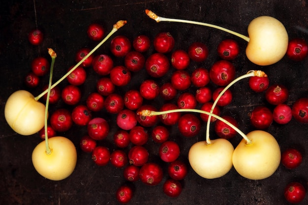 Vegetarian food concept Sweet juicy red currants and yellow cherries on a dark background View from above