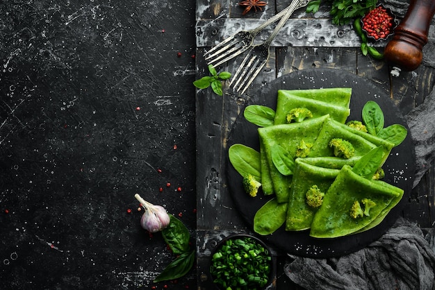 Vegetarian Food Green Spinach pancakes with vegetables on a black stone plate Top view Free space for your text