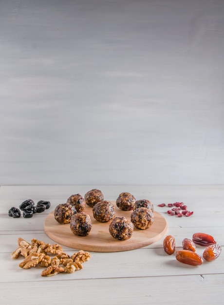 Vegetarian food, homemade energy balls of walnuts, dates, prunes, cranberries and honey on white background with copy space