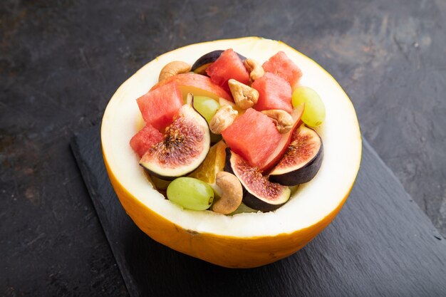 Vegetarian fruit salad of watermelon, grapes, figs, pear, orange, cashew  on slate board  .