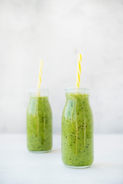 Vegetarian green smoothie with vegetables and fruit in glass bottles, selective focus