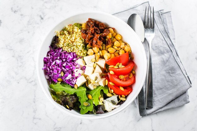 Vegetarian, healthy, detox food concept. Vegetarian buddha bowl. Raw vegetables, tofu and bulgur in white bowl with cutlery. Top view