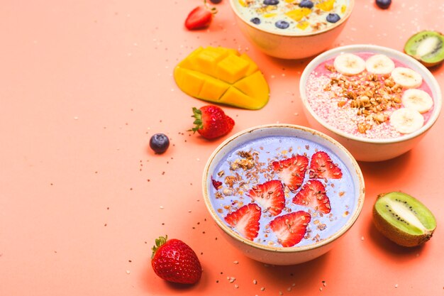 Vegetarian healthy food made from multi-colored smoothies with matches and berries on a bright pink table