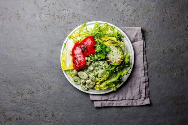 Vegetarian lettuce beans salad with grilled avocado and bell pepper. Top view