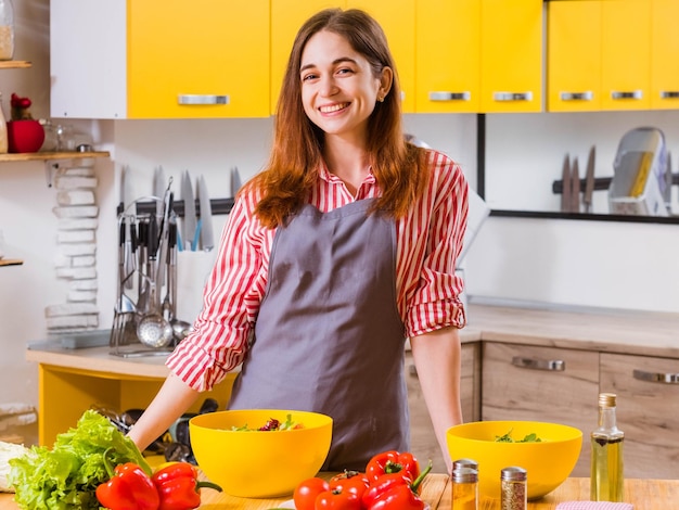 Vegetarian lifestyle Smiling happy lady in modern kitchen Fresh ingredients for salad on table