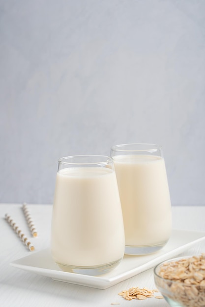 Latte d'avena vegetariano con gusto cremoso di farina d'avena senza lattosio e senza latticini nel bicchiere sul tavolo