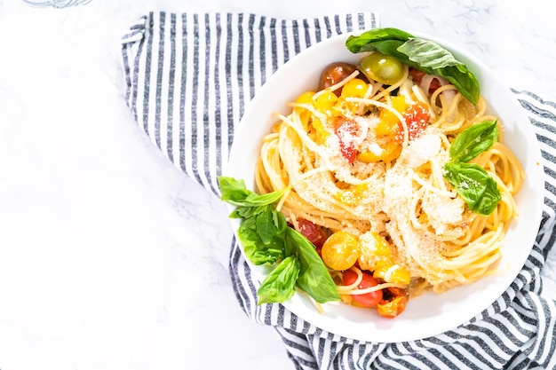 Vegetarian pasta with cherry tomatoes and fresh basil on a white plate.