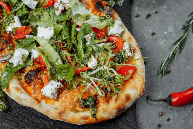 Vegetarian pizza with cheese tomatoes and greens.