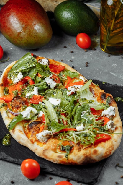 Vegetarian pizza with cheese tomatoes and greens.