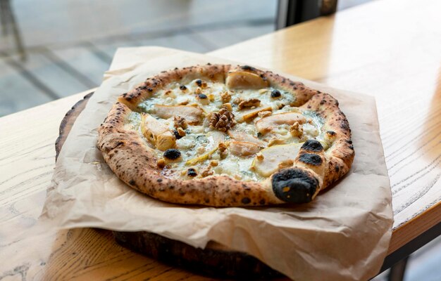 Vegetarian pizza with pear vegan cheese gorgonzola and walnuts on board on rustic wooden table