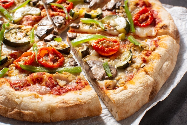 Pizza vegetariana con zucchine pomodori peperoni e funghi su tavola di legno