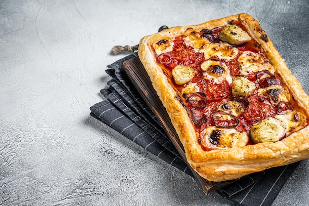 Vegetarian puff pastry pizza with artichoke mozzarella tomatoes and cheese White background Top view Copy space