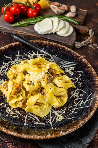 Vegetarian ravioli Pasta with Mozzarella, parmesan cheese and Tomato. Dark background. Top view.