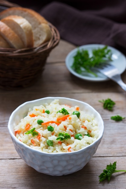 Photo vegetarian rice dish with vegetables and green peas on a wooden surface