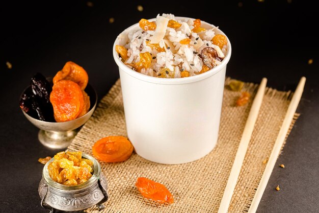 vegetarian Rice porridge with raisins and dried apricots in a cardboard container, on burlap,