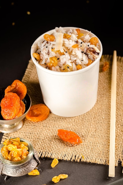 vegetarian Rice porridge with raisins and dried apricots in a cardboard container, on burlap,