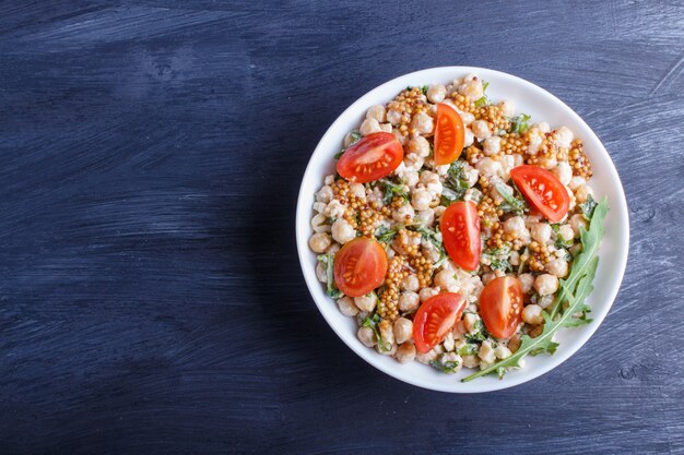 Vegetarian salad of boiled chickpeas, cheese, arugula, mustard and cherry tomatoes