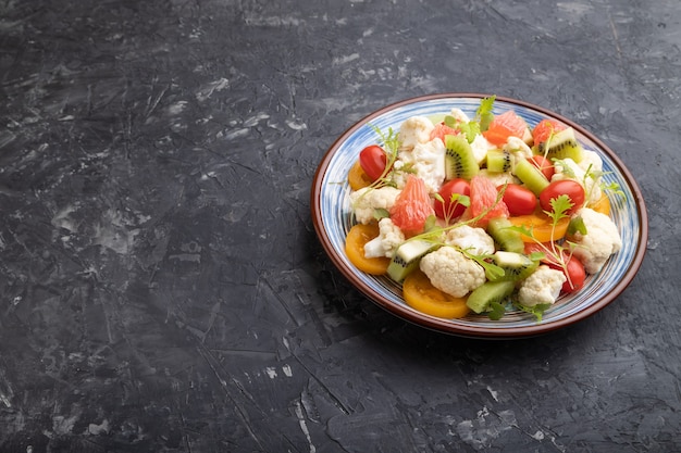 Vegetarian salad of cauliflower cabbage, kiwi, tomatoes, microgreen sprouts