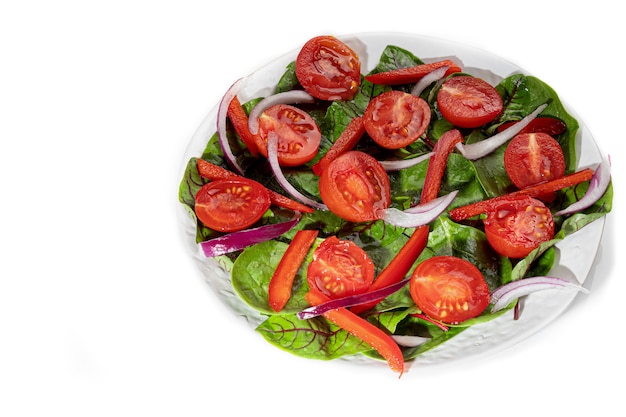 Вегетарианский салат из помидоров черри, шпината, красного лука и болгарского перца с маслом. На белом фоне. Изолировать. Скопируйте пространство.