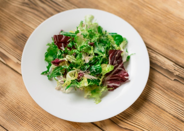 Vegetarian salad of fresh vegetables on a white plate on a wooden background