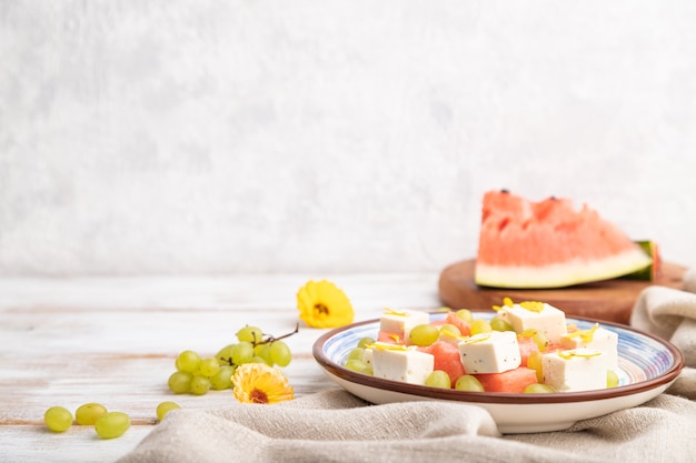 Vegetarian salad with watermelon, feta cheese, and grapes on blue ceramic plate