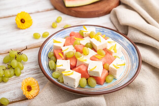 Vegetarian salad with watermelon, feta cheese, and grapes on blue ceramic plate