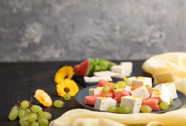 Vegetarian salad with watermelon, feta cheese, and grapes on blue ceramic plate