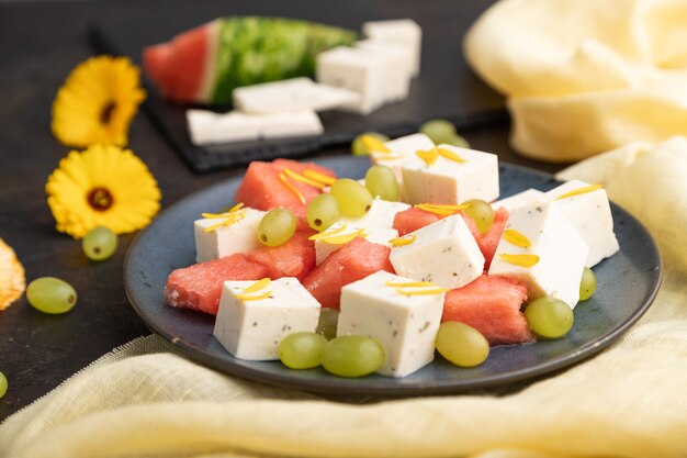 Vegetarian salad with watermelon, feta cheese, and grapes on blue ceramic plate