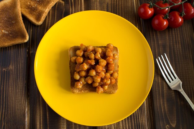 Foto sandwich vegetariano con ceci in salsa di pomodoro sulla piastra gialla.vista dall'alto.