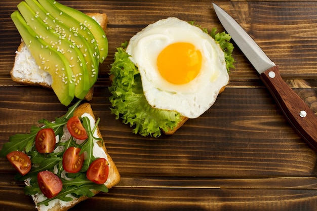 茶色の木製の背景に野菜と卵と野菜のサンドイッチ