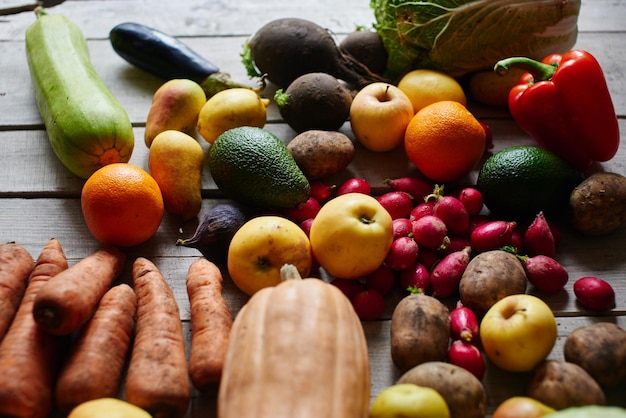 Vegetarian set consisting of vegetables and fruits lying on the wooden table closeup